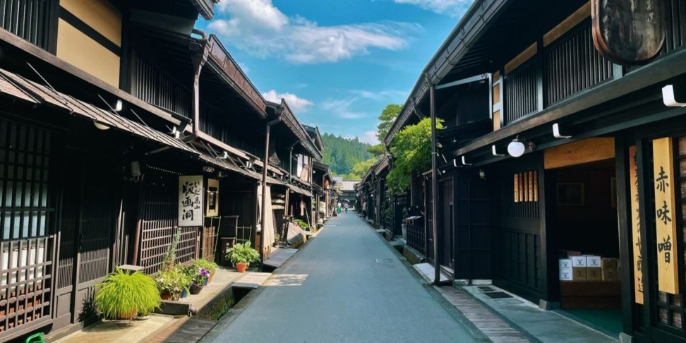 Daytime photo of a narrow street in Takayama Japan lined with restored historical homes and businesses.